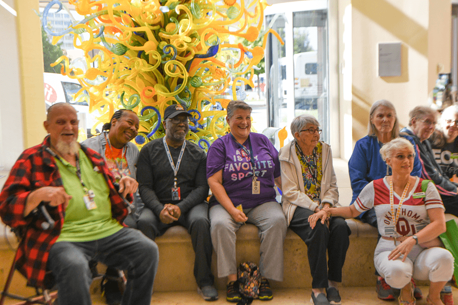 Elderly group of visitors sitting in front of a tower of glass made by Dale Chihuly.