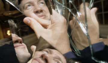 Film still from Lynch/Oz with David Lynch's face reflected in shards of broken mirror.