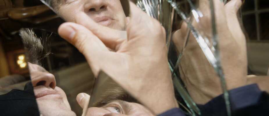 Film still from Lynch/Oz with David Lynch's face reflected in shards of broken mirror.