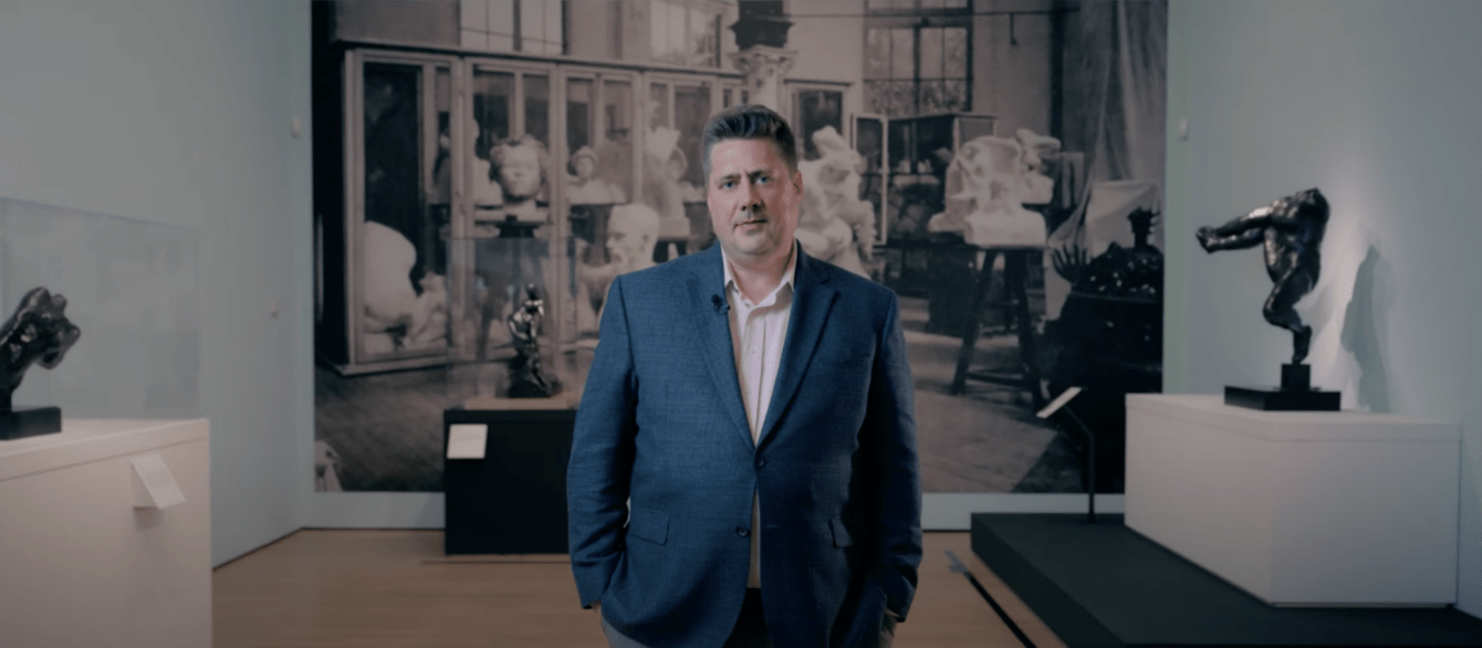 President and CEO Michael J. Anderson standing in an art gallery with Auguste Rodin pieces in the background.