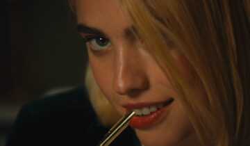 SANCTUARY Still 1 courtesy of NEON Margaret Qualley bites the cap of a pen