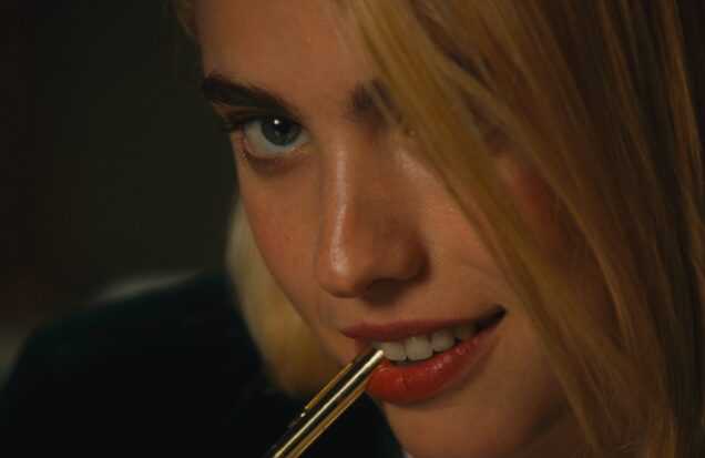 SANCTUARY Still 1 courtesy of NEON Margaret Qualley bites the cap of a pen