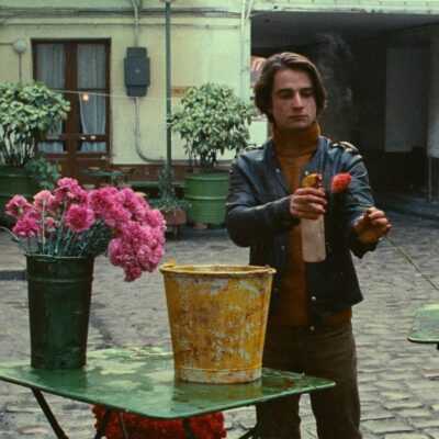 A film still from Bed and Board with Antoine Doinel spraying a flower with water.