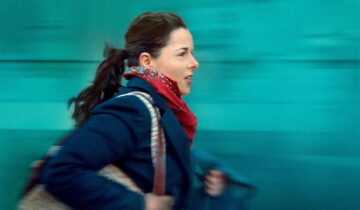 A film still from Full Time with Laure Calamy running against a blue background.