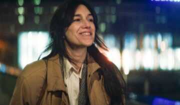 A film still Passengers of the Night with Charlotte Gainsbourg walking and smiling against a nighttime cityscape.