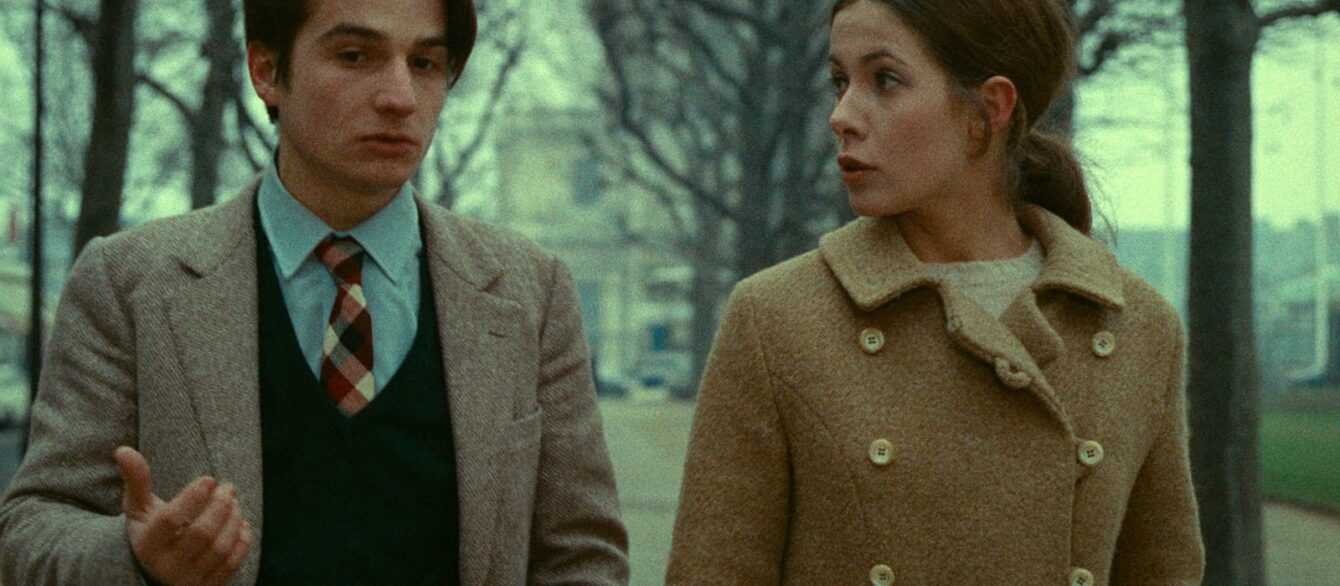 A film still from Stolen Kisses shows Antoine Doinel and a young woman walking and talking in a park.