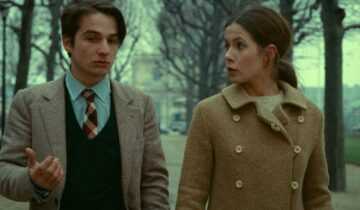 A film still from Stolen Kisses shows Antoine Doinel and a young woman walking and talking in a park.