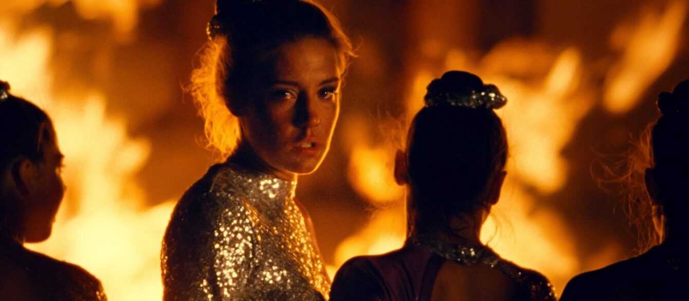 A film still from the The Five Devils of Adèle Exarchopoulos in a gymnastics uniform with flames behind her.