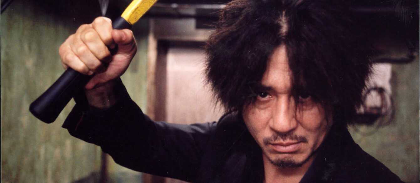 A film still from Oldboy with a man brandishing a hammer.