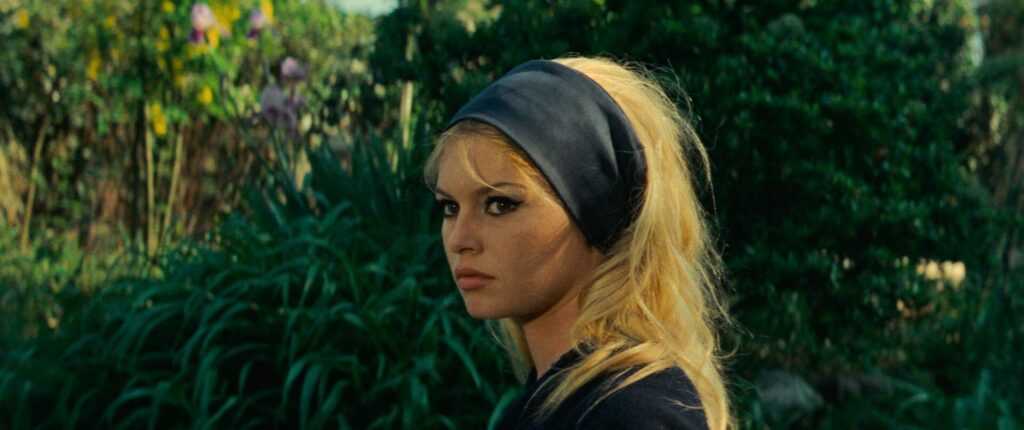 A film still from Godard's Contempt with Brigitte Bardot in profile wearing a black headband.