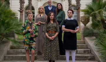Film still from the Origin of Evil with a group of people standing on the steps of a large house