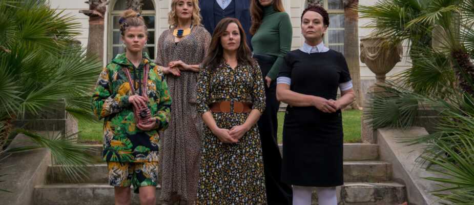 Film still from the Origin of Evil with a group of people standing on the steps of a large house