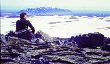 A film still from Time and Water. Icelandic Glaciological Society member, Árni Kjartansson, sits overlooking a glacier in Iceland. (Archival Materials Courtesy of Andri Snær Magnason)