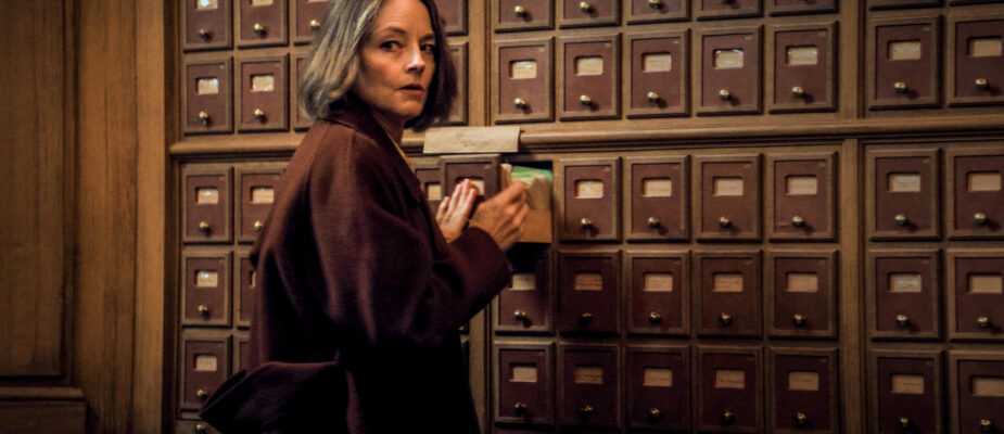 A woman stands in front of a wall of library card catalog drawers while opening a drawer in a scene from A Private Life.