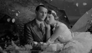 A black-and-white image of a bride and groom embracing during a wedding scene from Le Million.