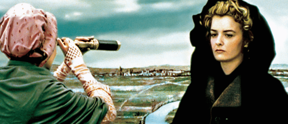 A woman in a dark coat looks away while another woman views the landscape through binoculars in a scene from The Lady and the Duke.